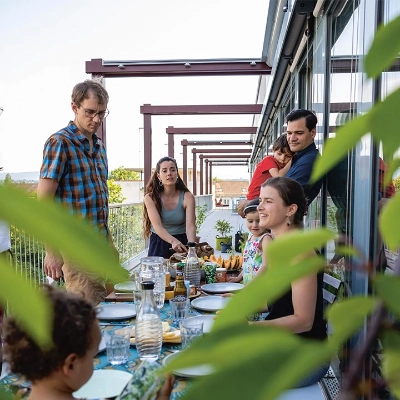 Menschen beim Mittagessen auf einer Dachterrasse eines Areals