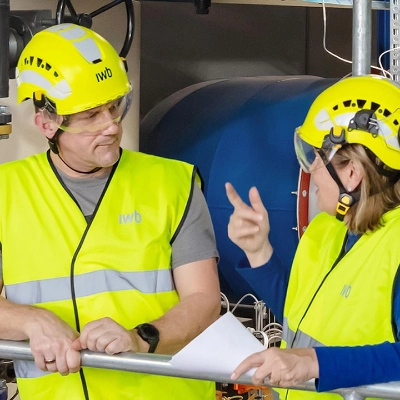 Ein Mann und eine Frau stehen in persönlicher Schutzausrüstung im Fernheizkraftwerk Volta.