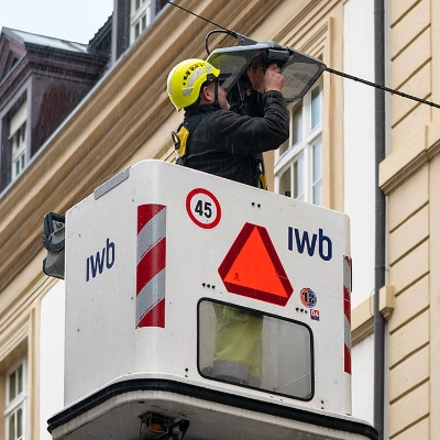 Mann steht in im Korb eines Skyworkers und arbeitet an einer Leuchte.