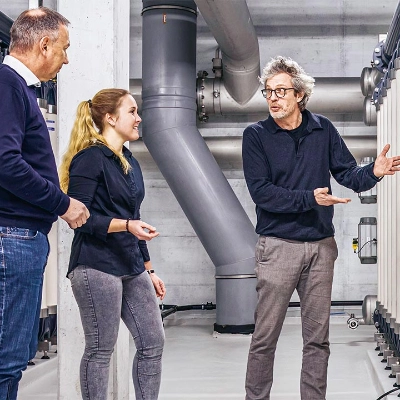 Drei Personen stehen vor einer Wasseraufbereitungsanlage