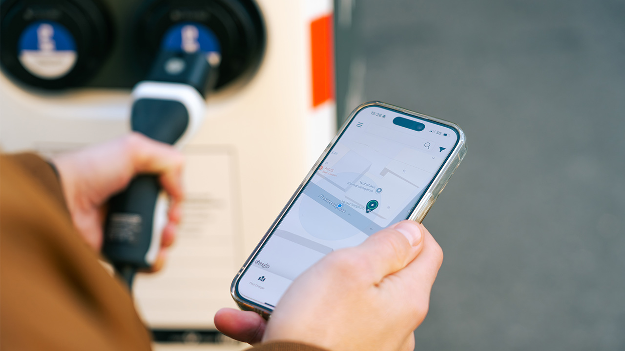 Mann lädt sein E-Auto mit der IWB E-Mobility App auf seinem Smartphone