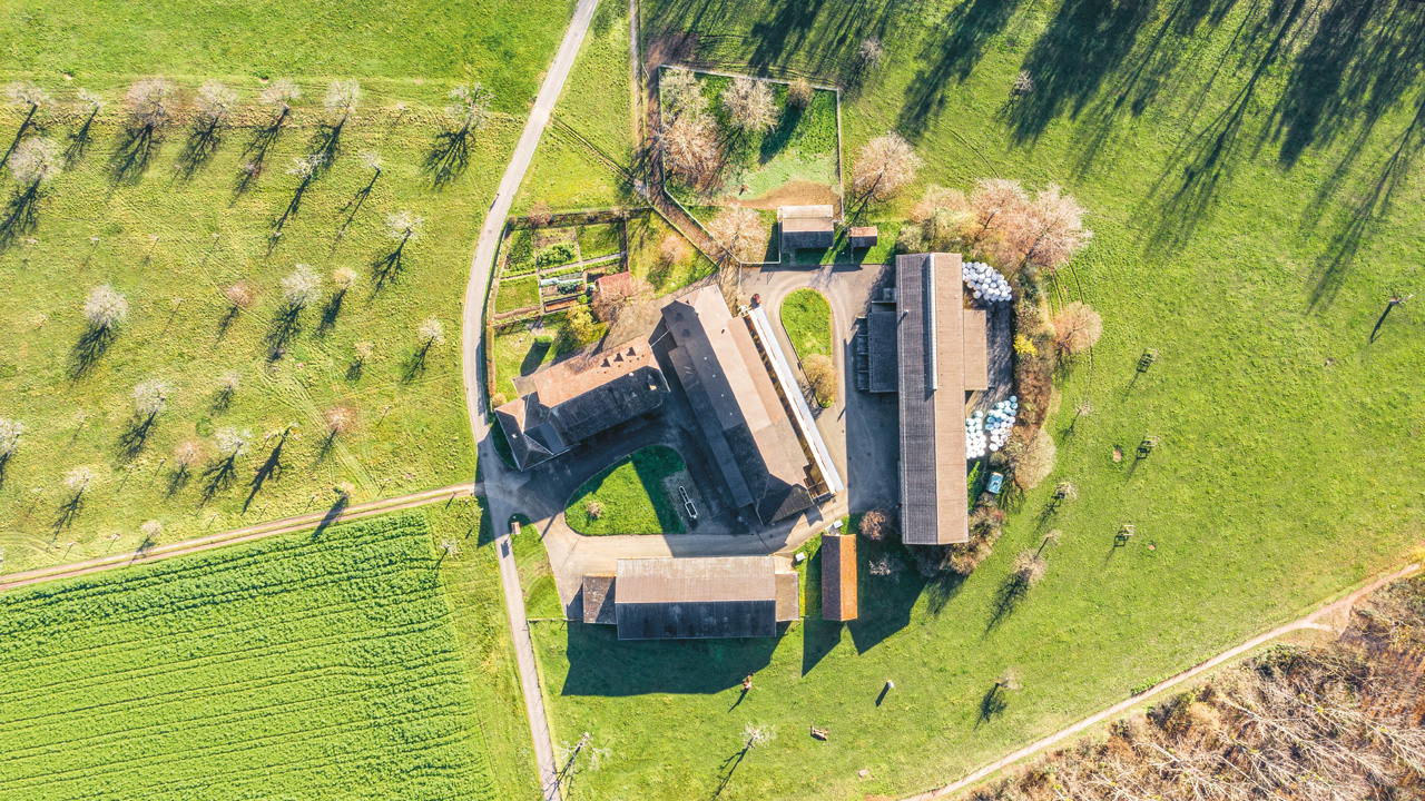 Ein Bauernhof mit mehreren Gebäuden aus der Vogelperspektive.