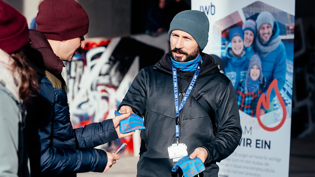 Mitarbeiter von IWB verteilt Schlauchschal