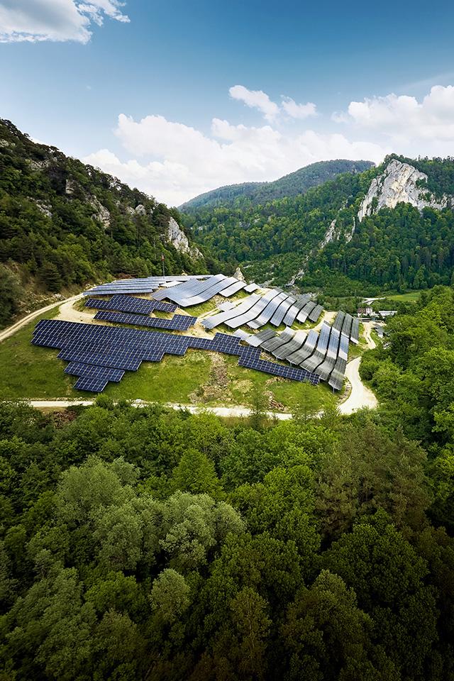 Eine Solaranlage, deren Form an einen Schildkrötenpanzer erinnert, umringt von grünen Bäumen.