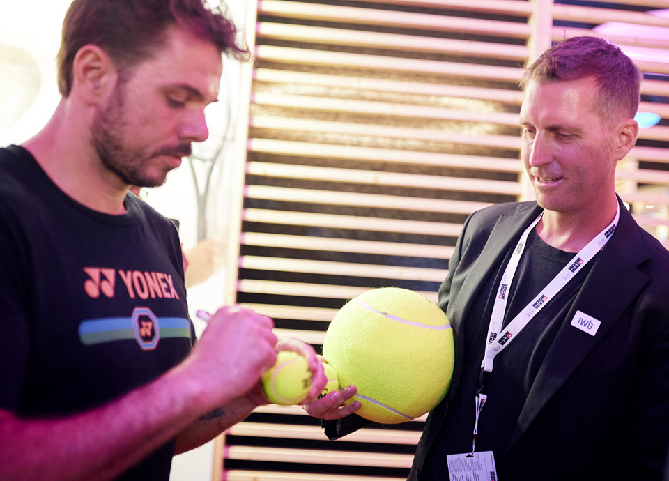 Tennis-Star Stan Wawrinka signiert einen Tennisball. 