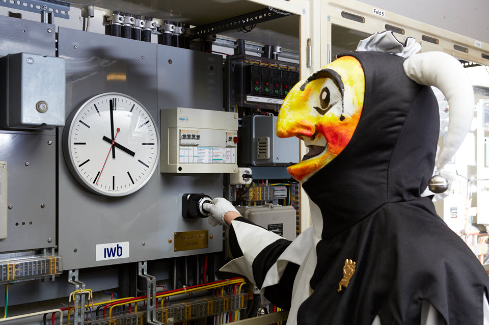 Ein verkleideter Mann steht vor dem Schalter, um am Fasnachtsmorgen um 04:00 Uhr das Licht abzulöschen.