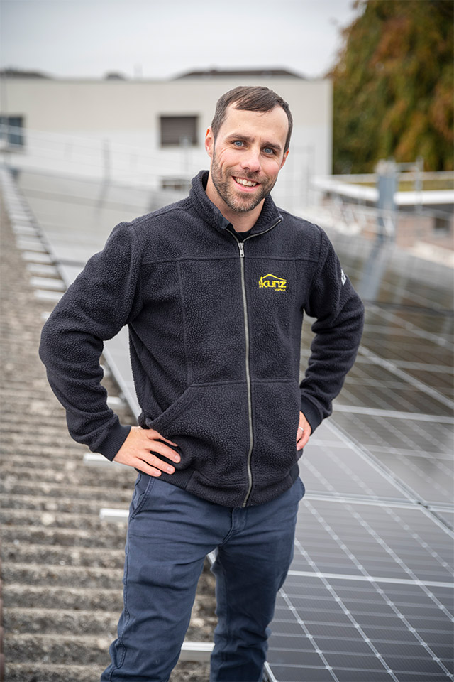 Nico Knubel auf dem Dach mit einem Solarmodul in der Hand.