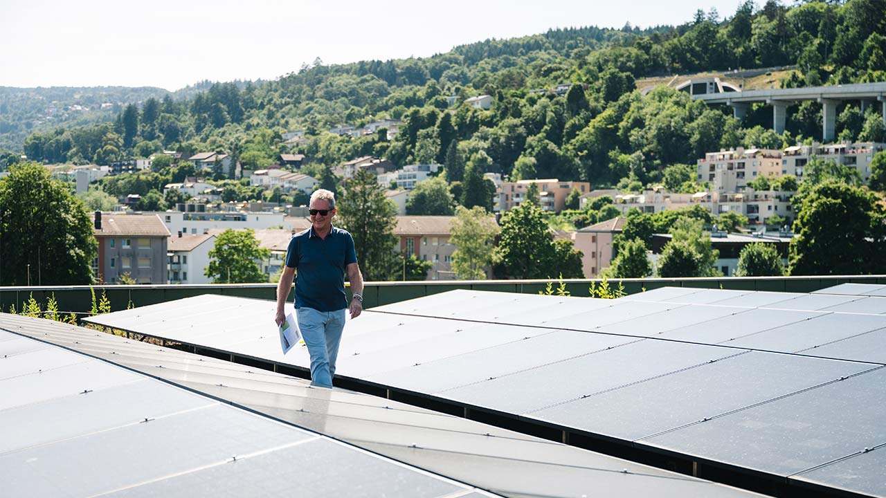 Mann läuft auf dem Dach neben der installierten Solaranlage durch