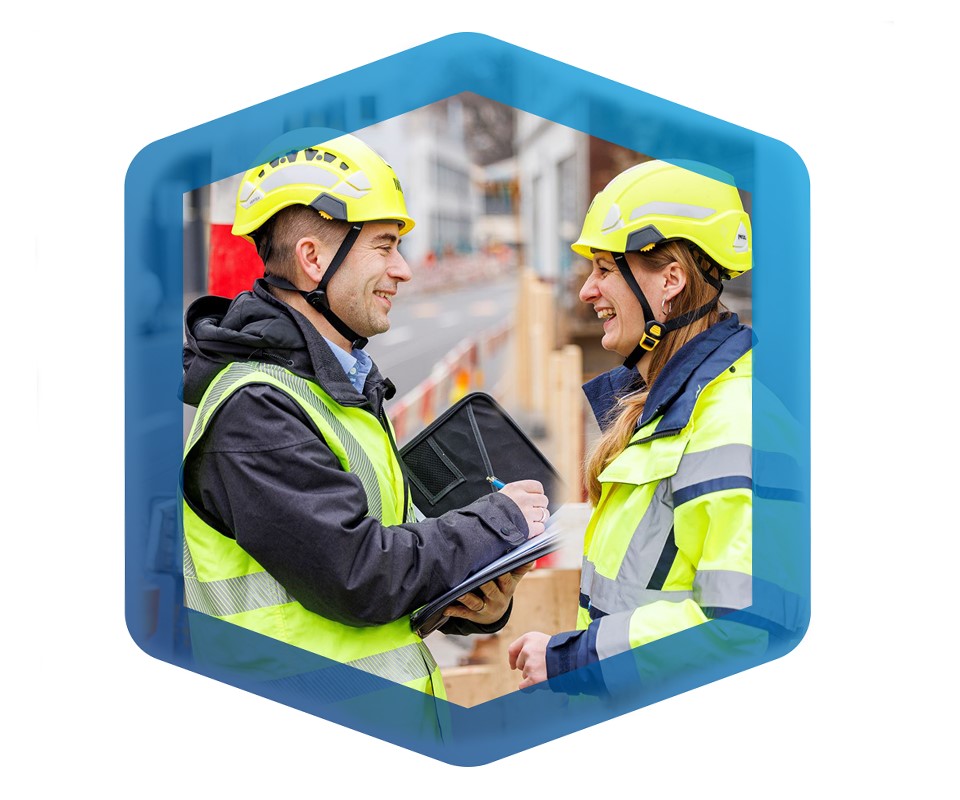 Eine Frau und ein Mann auf einer Baustelle im Gespräch.