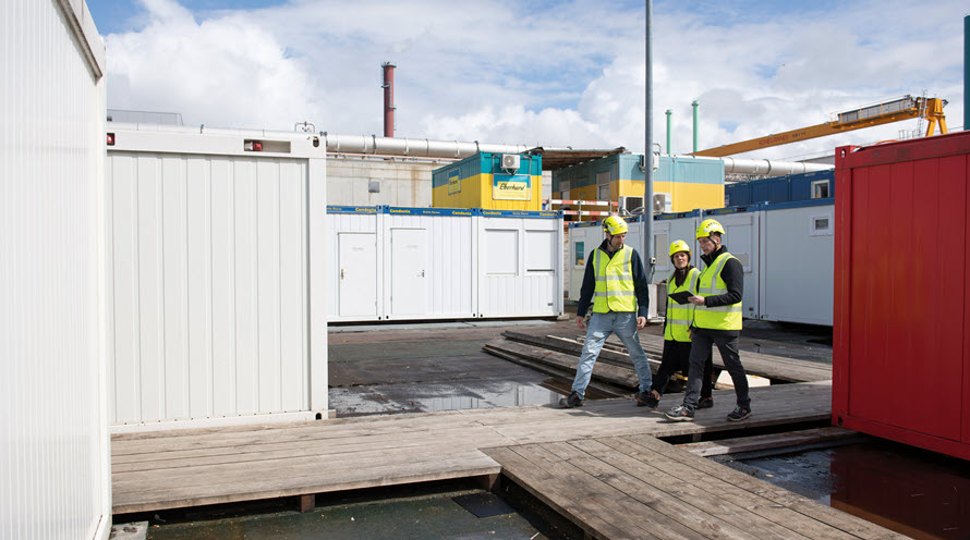 Philipp Frey, Ingela Lakatos und Beat Spengler sind auf der Baustelle zu Fuss unterwegs, wo künftig die Abwasserreinigungsanlage stehen wird. Um sie herum sie Baucontainer. 