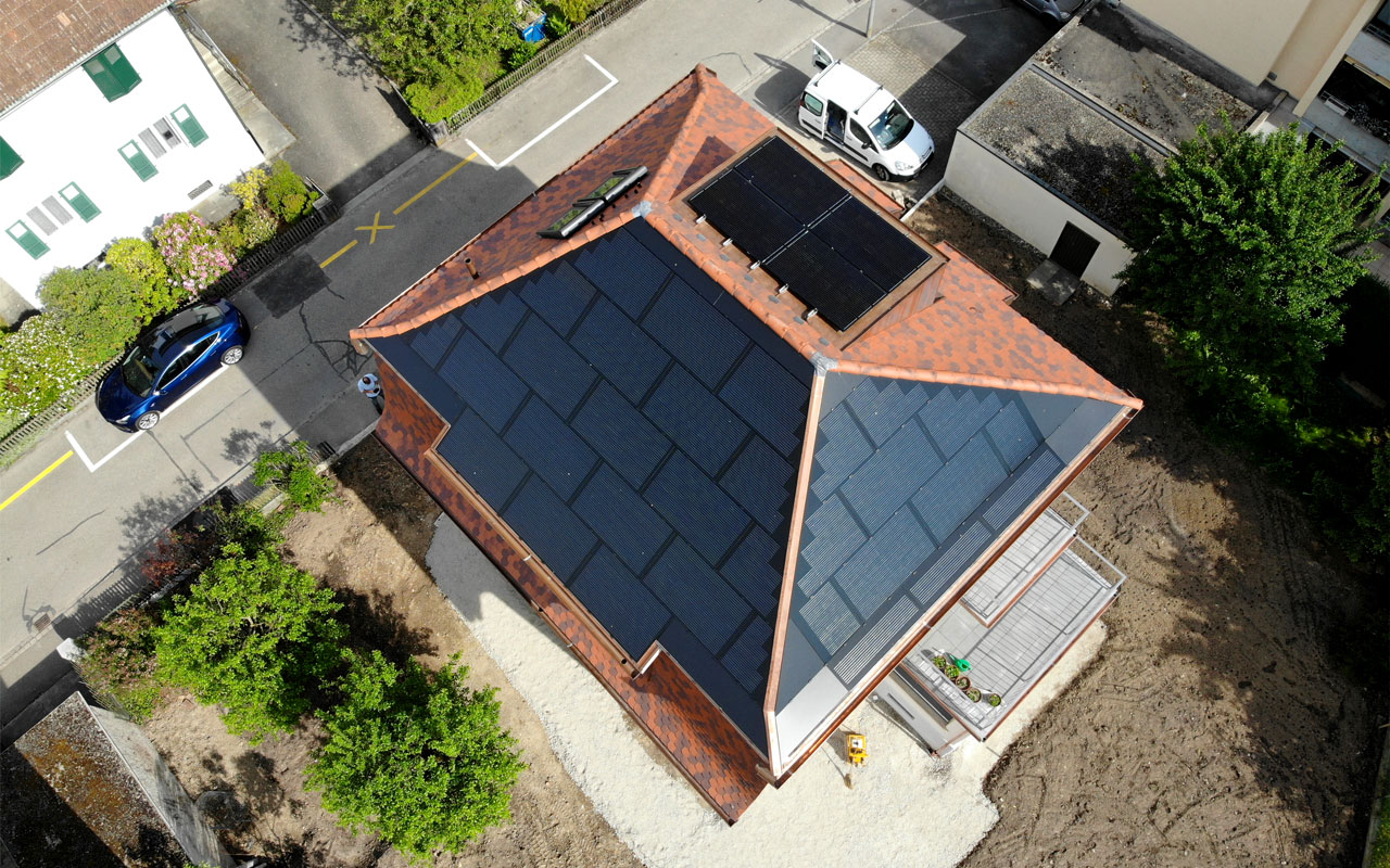 Ein Einfamilienhaus aus der Vogelperspektive. Zwei Dachseiten und ein Erker sind mit Solarpanels bedeckt.