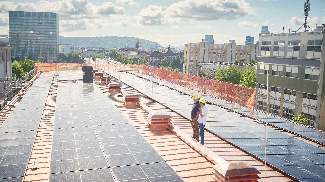 Jens Baumann und Dominic Kimmig auf dem Dach des Unterwerks Volta. Seit Juli 2026 produziert die neue Photovoltaikanlage von IWB hier Solarstrom mit einer Leistung von 193,8 kWp. 