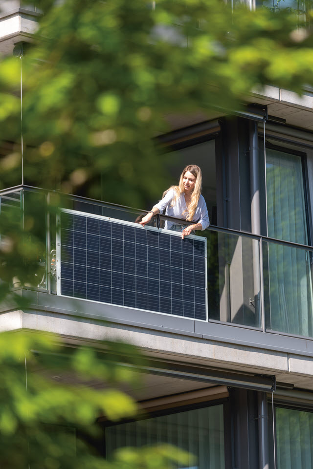 Anna Di Matteo steht am Balkon. Am Gelände ist eine Balkon-Solaranlage montiert.