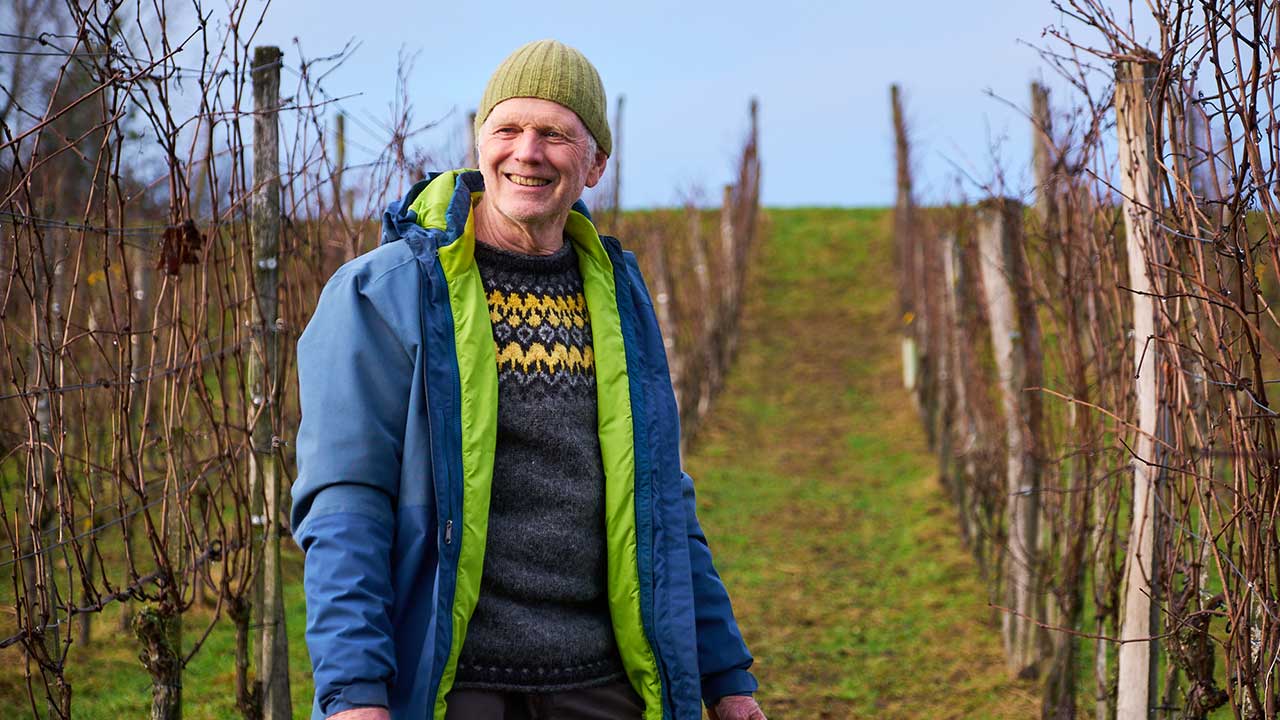 Winzer im Weinberg lacht in die Kamera