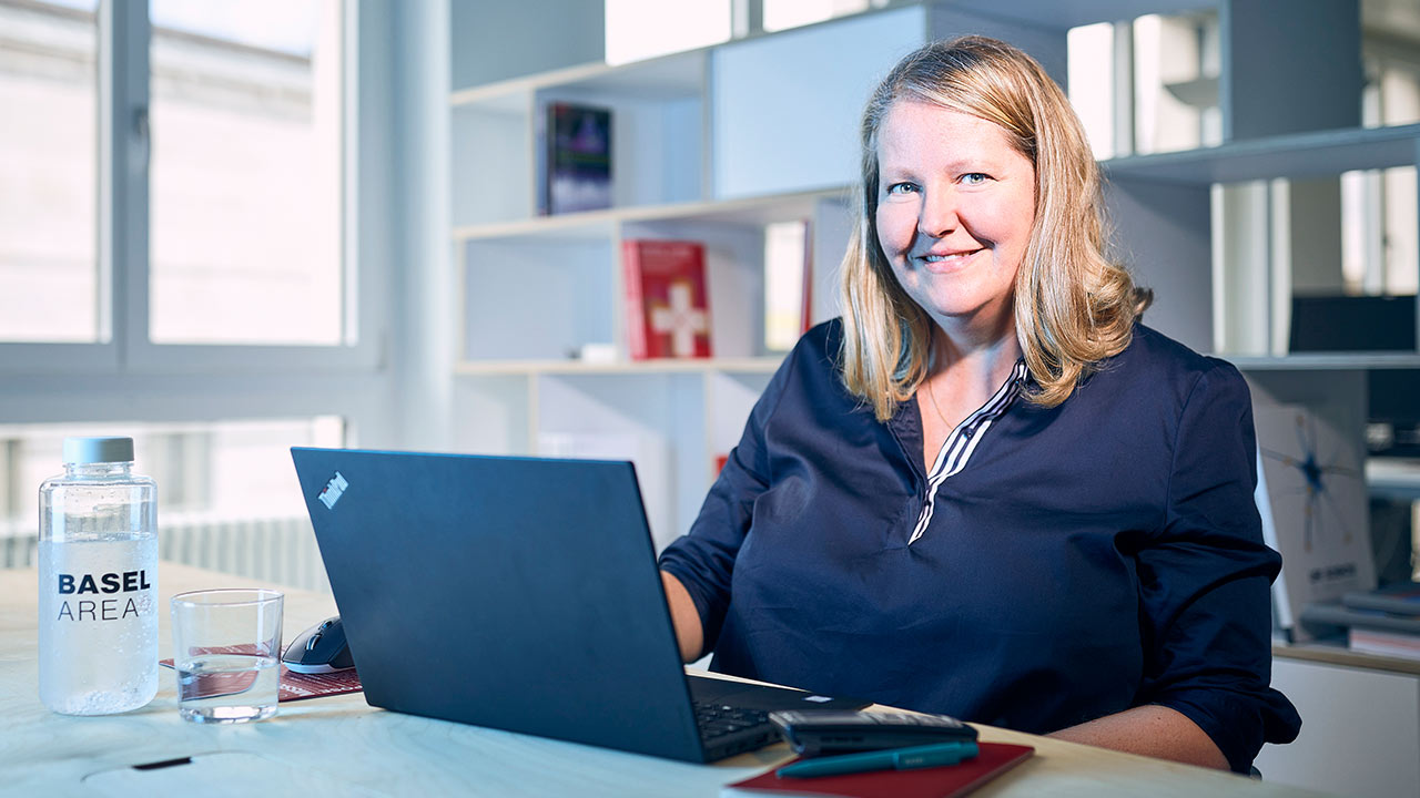 Eine Frau sitzt in einem hellen Büro vor einem Laptop.