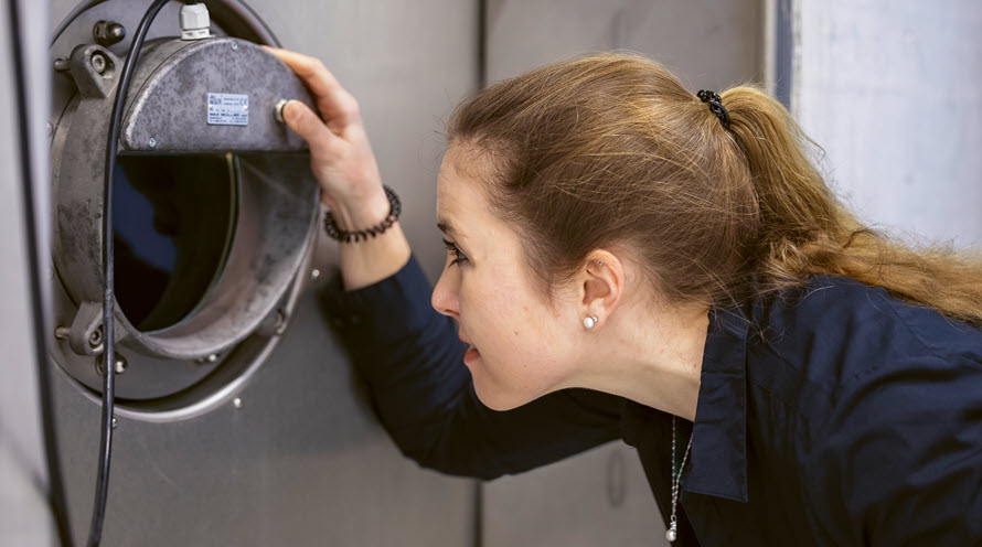 Andrea Engler schaut durch ein kleines Fenster in einen riesigen Behälter mit Wasser drin.