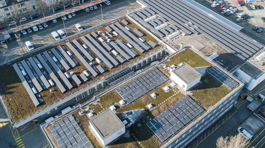 Blick von oben auf ein Industrieareal, auf dem Solarpanels installiert sind.