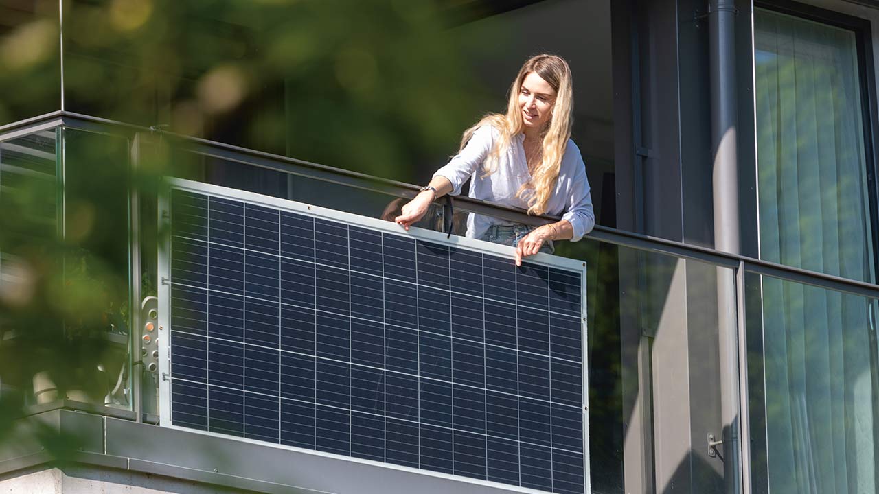 Frau montiert Balkonsolaranlage