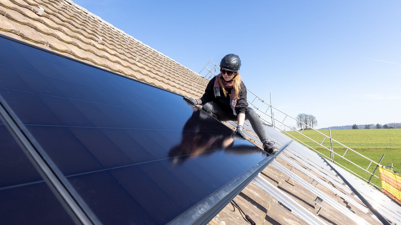 Eine Senero-Mitarbeiterin montiert ein PV-Modul auf einem Dach.