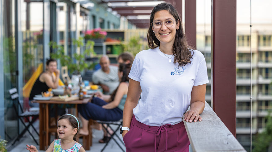 Porträt von Shanti Grand. Im Hintergrund sitzen ihre Mitbewohnerinnen und Mitbewohner am Tisch auf der Terrasse.