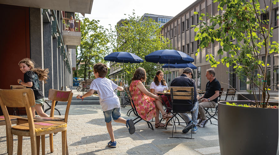 Vier Menschen sitzen draussen an einem Tisch eines Cafés.