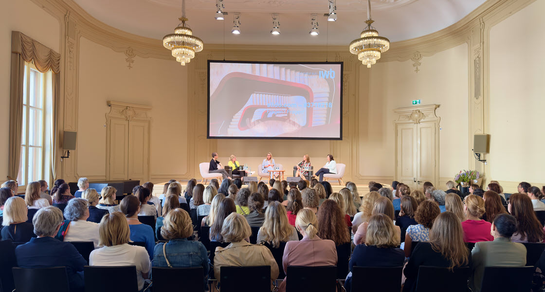 Fünf Frauen diskutieren auf einem Podium vor einem weiblichen Publikum.