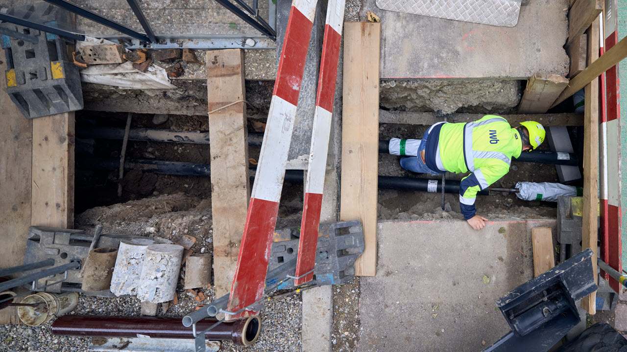 Arbeiter kontrolliert Installationen auf Fernwärme-Baustelle