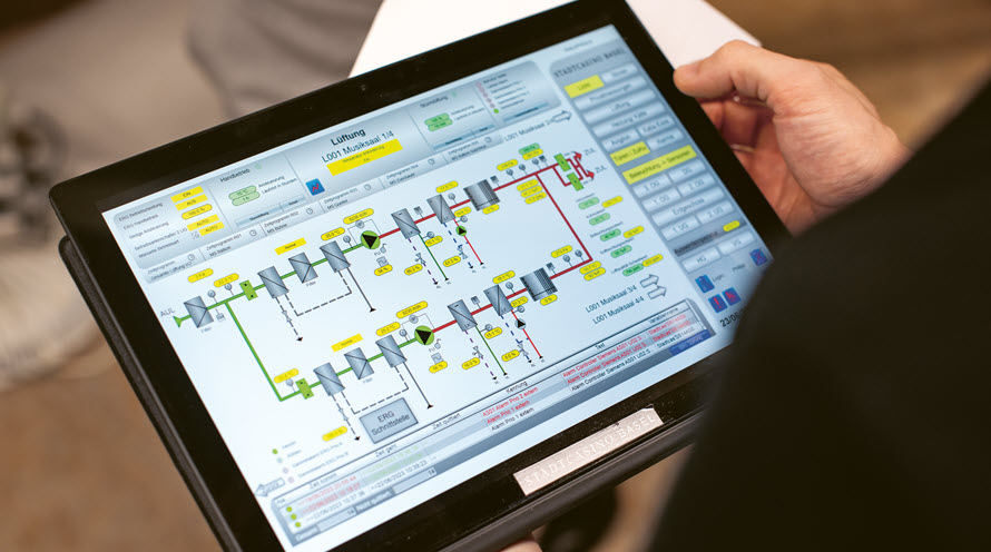 Jemand hält ein Tablet in Händen. Darauf sind Skizzen und Daten der Gebäudetechnik zu sehen.