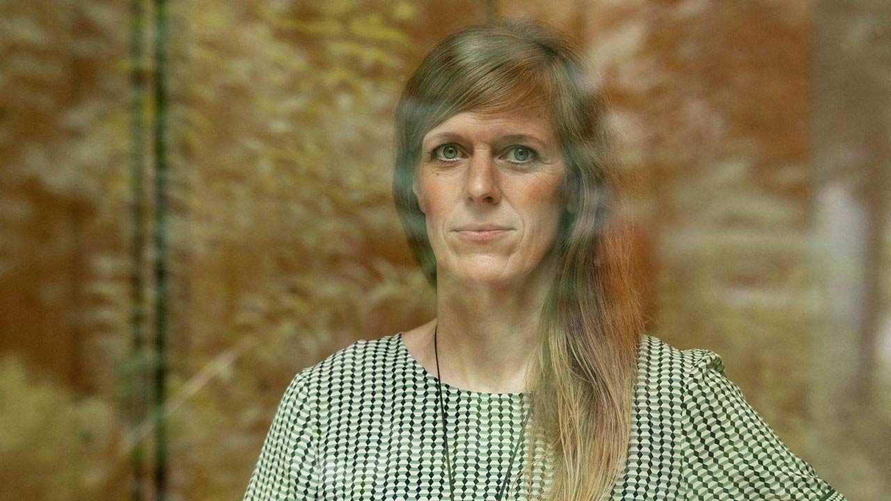 Dozentin Friederike Kluge blickt durch eine verspiegelte Fensterscheibe.