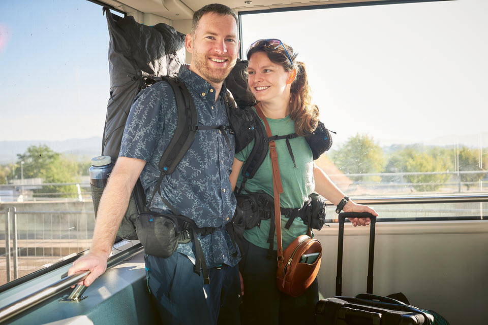 Ein Mann und eine Frau mit Rucksäcken und einem Koffer stehen im Bus.