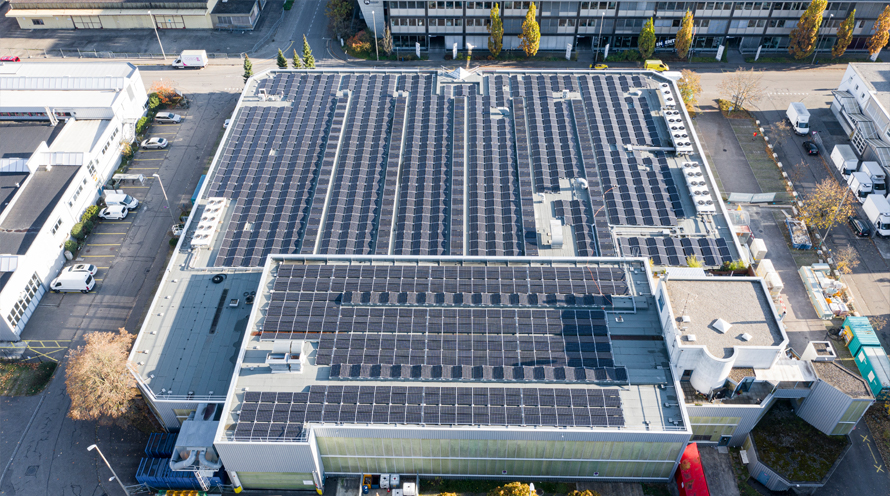 Luftansicht einer grossen Solaranlage auf einem Fabrikdach.