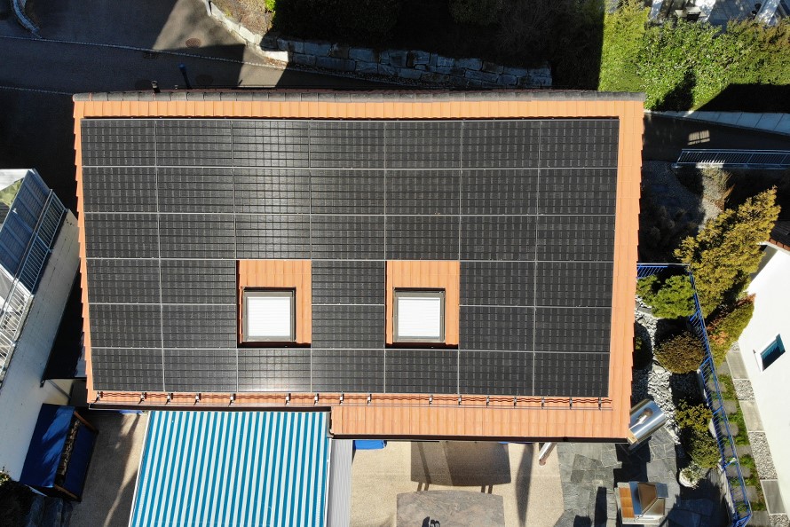 Ein Hausdach aus der Vogelperspektive.. Auf das Dach wurden nachträglich Solarpanels montiert.
