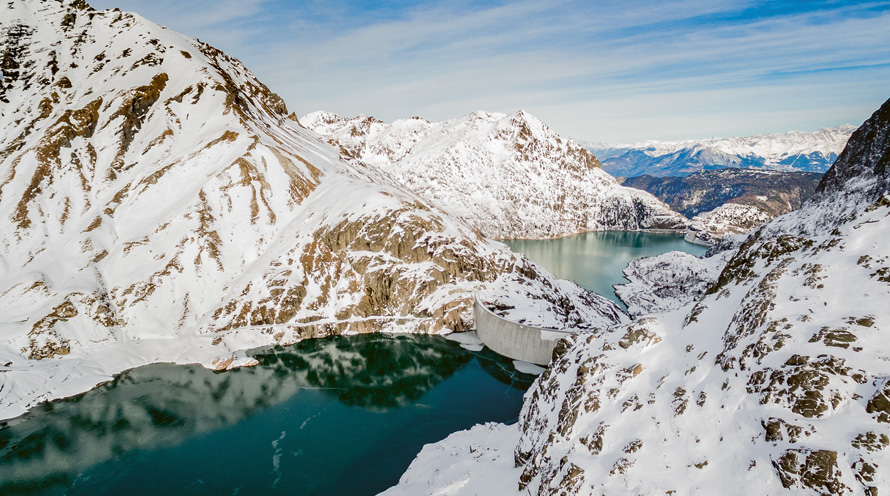 Blick auf zwei Stauseen in einer verschneiten Bergwelt. Der See links im Bild ist näher und höher gelegen als der See rechts.
