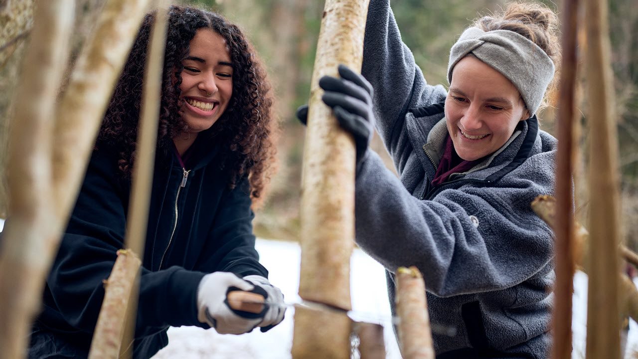 Eine Jugendliche und Lea Zaugg führen Waldarbeiten aus.