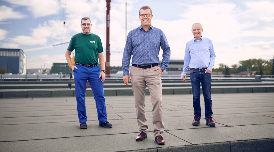 Drei Männer stehen auf dem Dach eines Industriegebäudes.