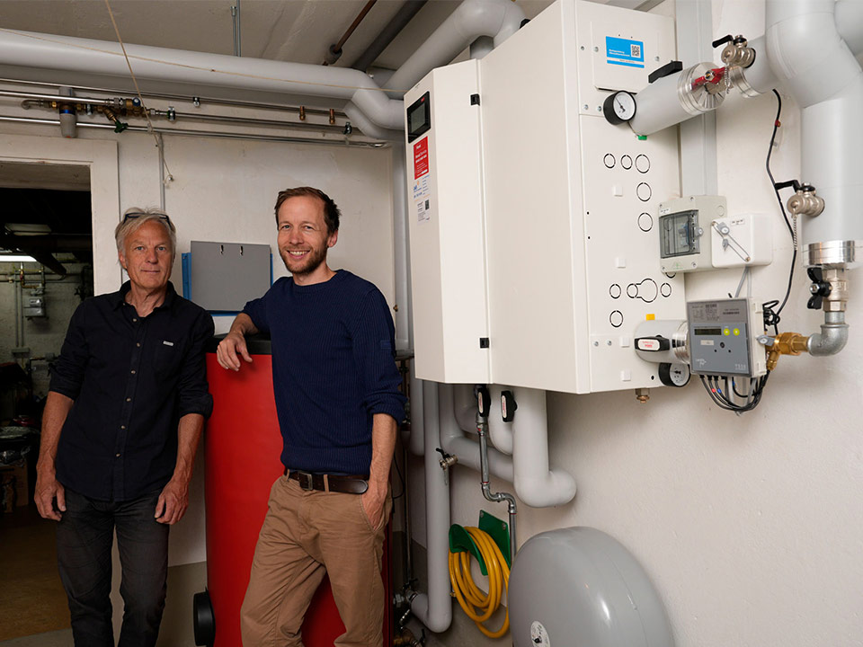 Zwei Männer stehen vor der Fernwärme-Unterstation im Keller