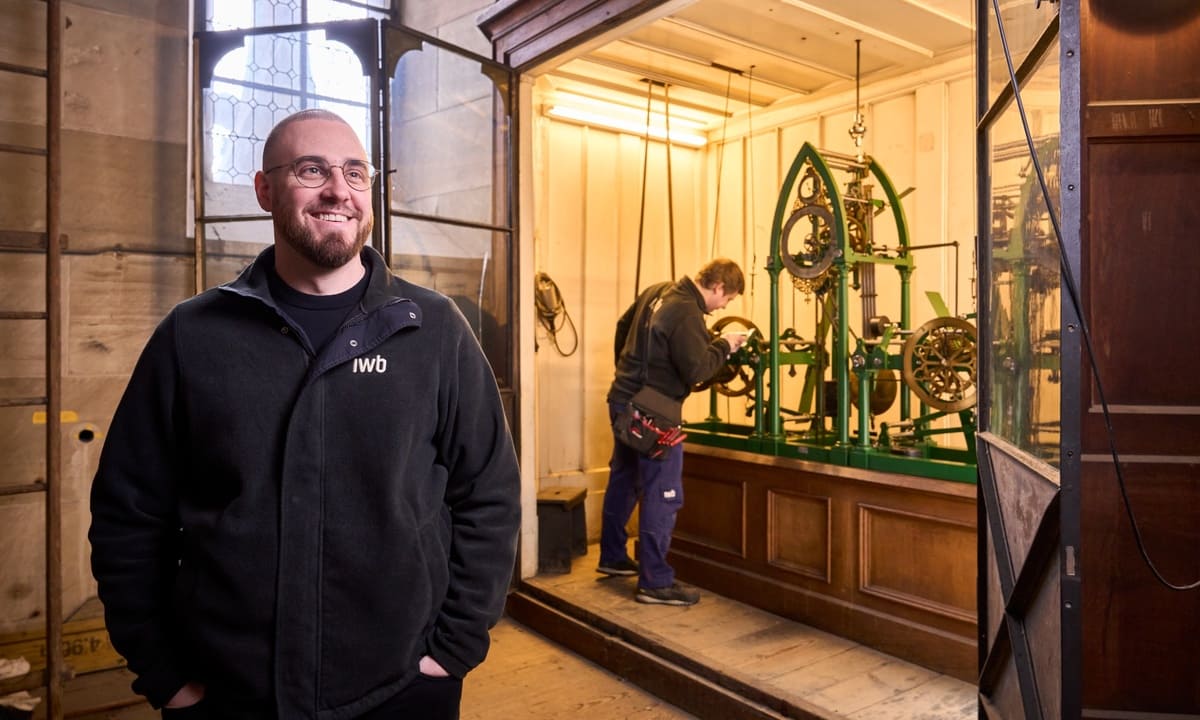 Thomas Jost, im Hintergrund das Uhrwerk der Pauluskirche und ein weiterer Mitarbeiter, der dieses kontrolliert. 