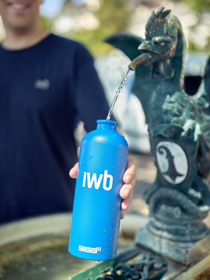 Mitarbeiter von IWB füllt Trinkflasche am Brunnen auf.