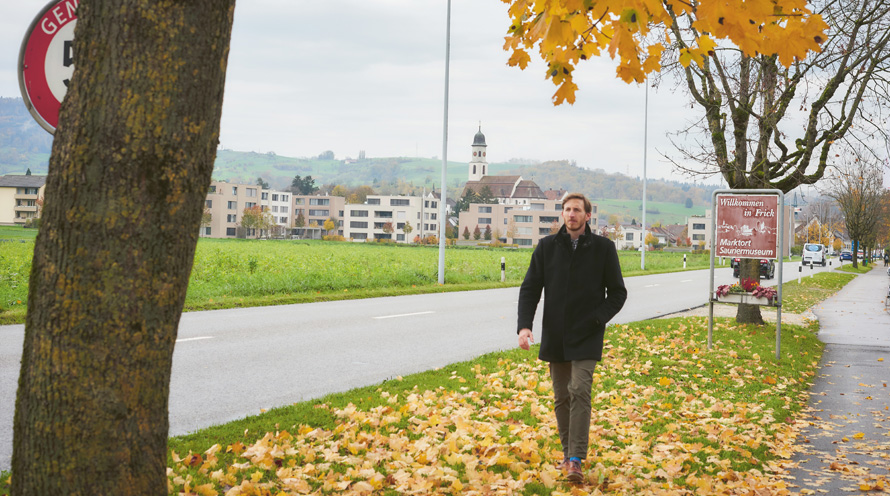 Ein Mann läuft durch Herbstlaub neben einer Strasse.