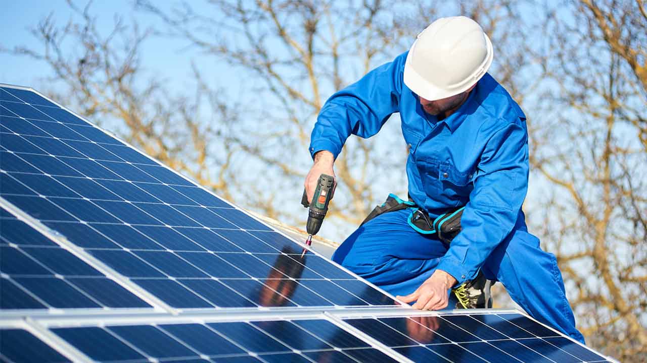 Mann installiert auf einem Dach Photovoltaikmodule.