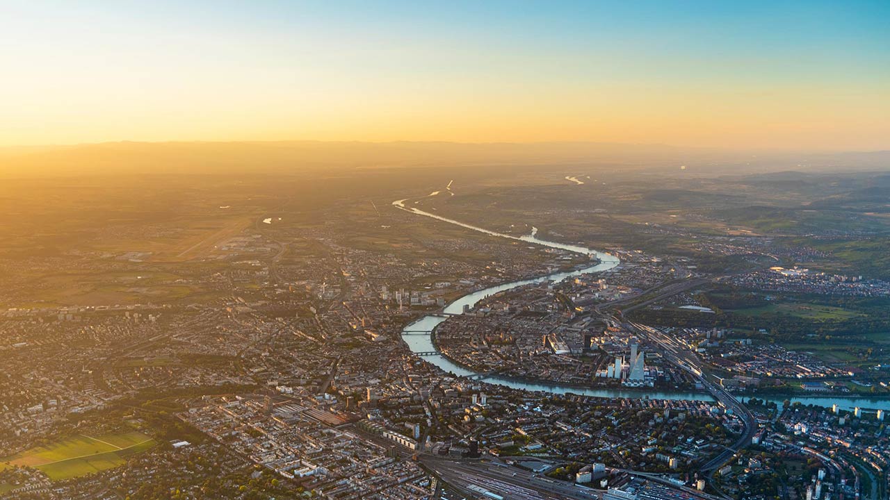 Mann in Schutzkleidung schweisst eine Fernwärmeleitung in einem offenen Graben.