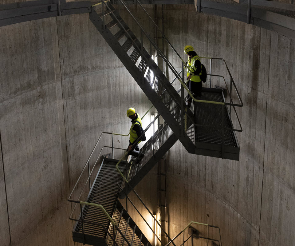 Philipp Frey und Ingela Lakatos steigen die Treppe herunter, die sie zum unterirdischen Energieleitungstunnel führt.