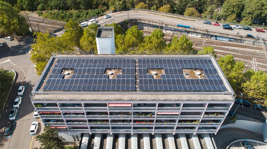 Blick von oben auf einen Wohnblock, auf dessen Dach sich eine Solaranlage befindet.